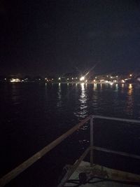 Illuminated city by river against clear sky at night