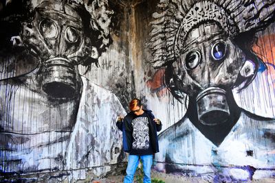 Portrait of man standing against graffiti wall