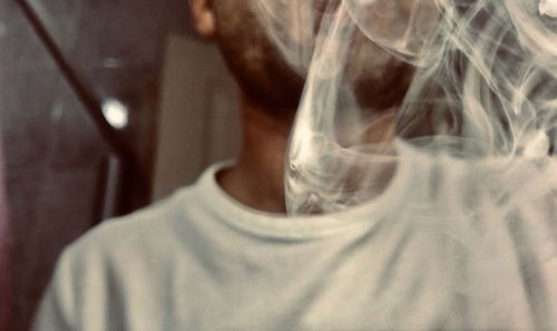 Midsection of man emitting smoke