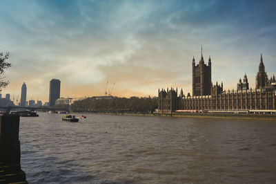 View of buildings by river against sky