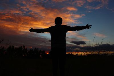 Silhouette man standing on field against sky during sunset