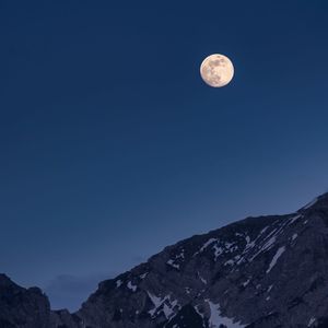 Low angle view of moon and mountains against clear blue sky
