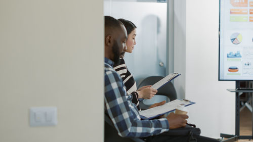 Side view of young woman using mobile phone in office