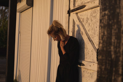 Side view of woman standing against wall