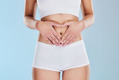 Midsection of woman standing against blue background