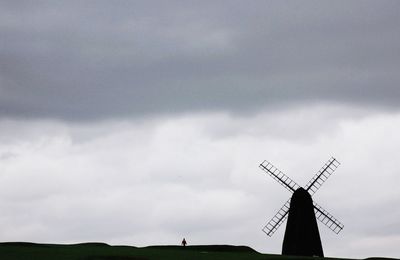 Low angle view of traditional windmill on field against sky