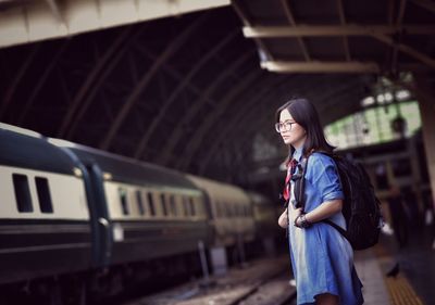 Side view of woman standing by train at railroad station