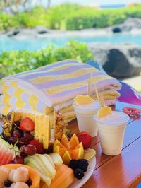 Tropical fruits and drinks near scenic lagoon and lush, green bushes