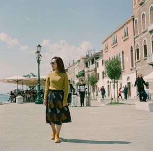 Woman standing with umbrella in city against sky