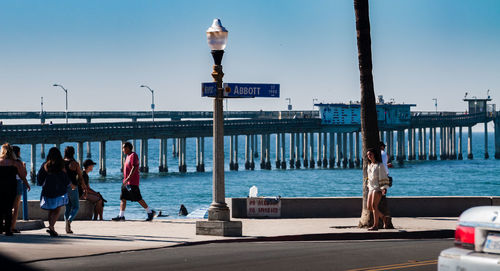 People at sea shore against clear sky