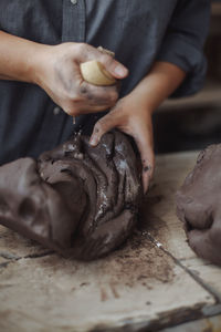 Middle-aged woman working in a pottery studio with clay