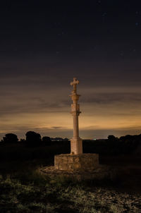 Cross on field against sky at night