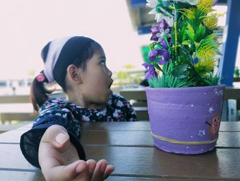 Close-up of cute boy looking at potted plant on table