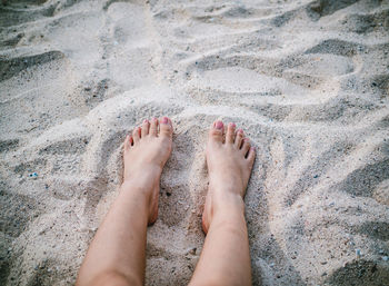 Low section of woman feet on sand