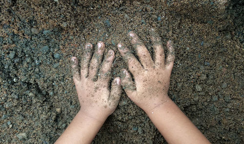 Close-up of hand touching sand