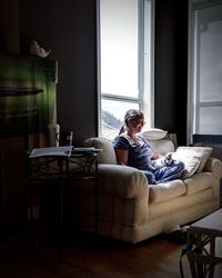 Woman with cat sitting on sofa at home