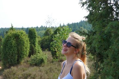 Side view of young woman in sunglasses against trees