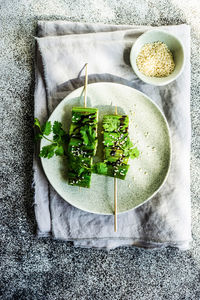 Bbq slices of okra with sesame seeds, coriander and soy sauce served on the plate