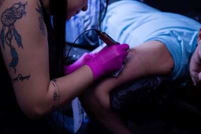 Woman tattooing on man arm at studio