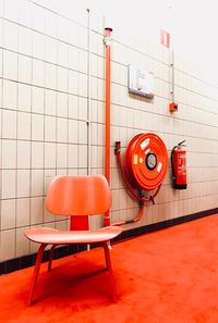 Orange chair on floor against tiled wall