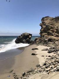 Rock formation on beach against clear sky