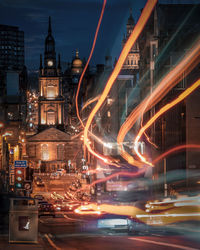 Light trails on street amidst buildings in city at night