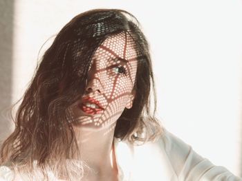 Beautiful woman with shadow on face against wall