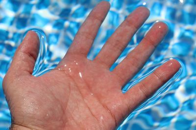 Cropped hand of man in swimming pool