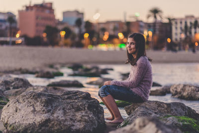 Portrait of young woman sitting on rock