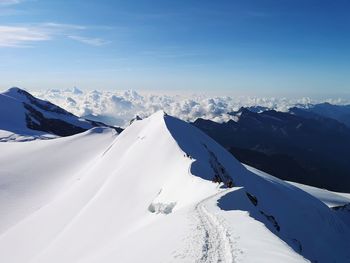 Scenic view of snow covered mountains against blue sky