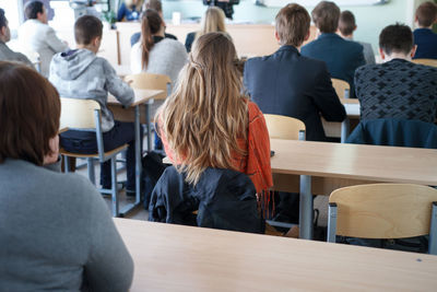 Rear view of people sitting on table