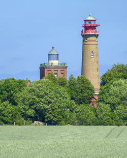 Lighthouse amidst trees and buildings against sky