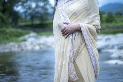 Midsection of woman standing by river