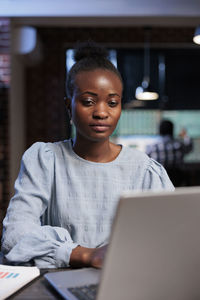 Portrait of young woman using laptop at table