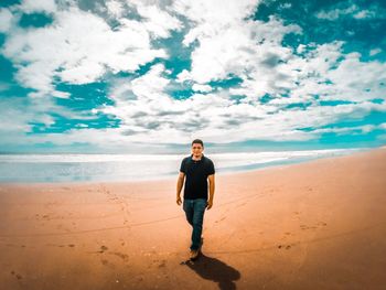 Full length of man standing on beach against sky