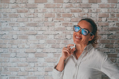 Young man wearing sunglasses while standing against wall