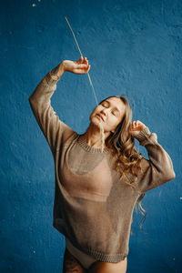 Full length of woman standing against blue wall