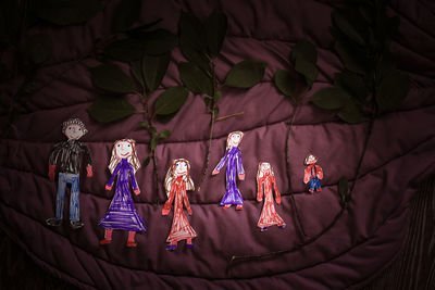 Carved figurines of family painted by  child. dark fabric background. happy childhood, creativity