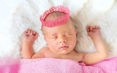 Cute baby wearing crown sleeping on bed at home