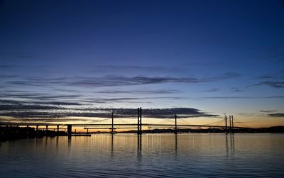 Silhouette bridge over river against sky at sunset