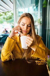 Young woman using mobile phone while sitting in cafe