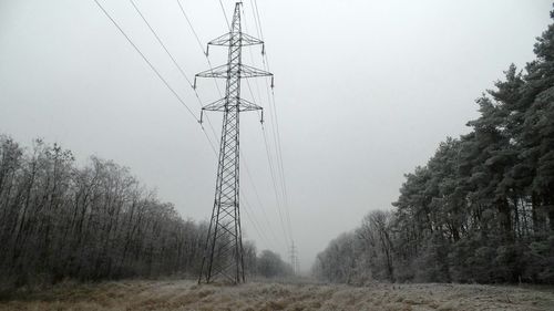 Low angle view of electricity pylon on field against sky