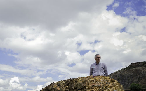 Man standing by rocks against sky