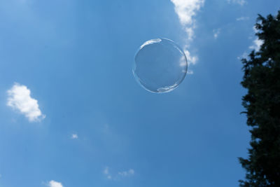 Low angle view of bubbles against blue sky