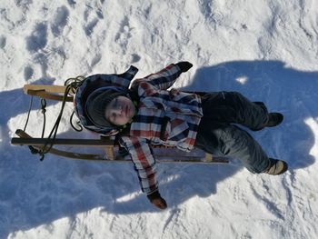 High angle view of boy sleeping on sled during winter