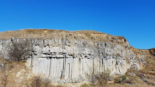 Low angle view of rock formation against clear blue sky