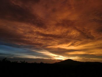 Silhouette landscape against dramatic sky during sunset