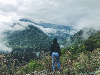 Rear view of man standing on mountain against sky