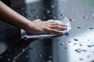 Close-up of woman hand on wet table