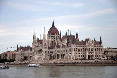 Buildings by river against sky